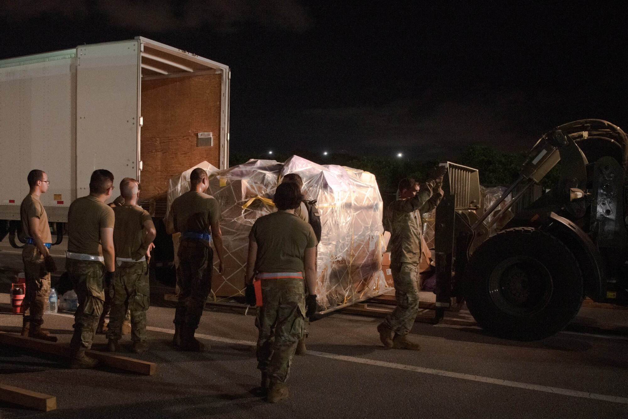 Airmen from Pacific Air Forces Air Postal Squadron Detachment 3, watch as a forklift lowers a pallet at Kadena Air Base, Japan, July 31, 2021. Det. 3 plays a critical role in ensuring the delivery of mail across the pacific. (U.S. Air Force photo by Airman 1st Class Stephen Pulter)