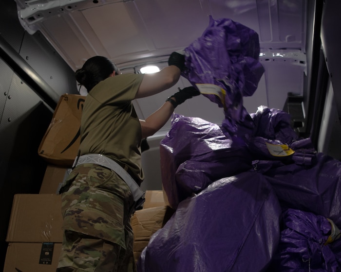 U.S. Air Force Master Sergeant Victoria Flores, Pacific Air Forces Air Postal Squadron Detachment 3 superintendent, loads mail onto a van at Kadena Air Base, Japan, July 31, 2021. Airmen from Det. 3 and the 18th Logistics Readiness Squadron ground transportation, worked tirelessly to serve mail to 11 U.S. military installations on Okinawa. (U.S. Air Force photo by Airman 1st Class Stephen Pulter)