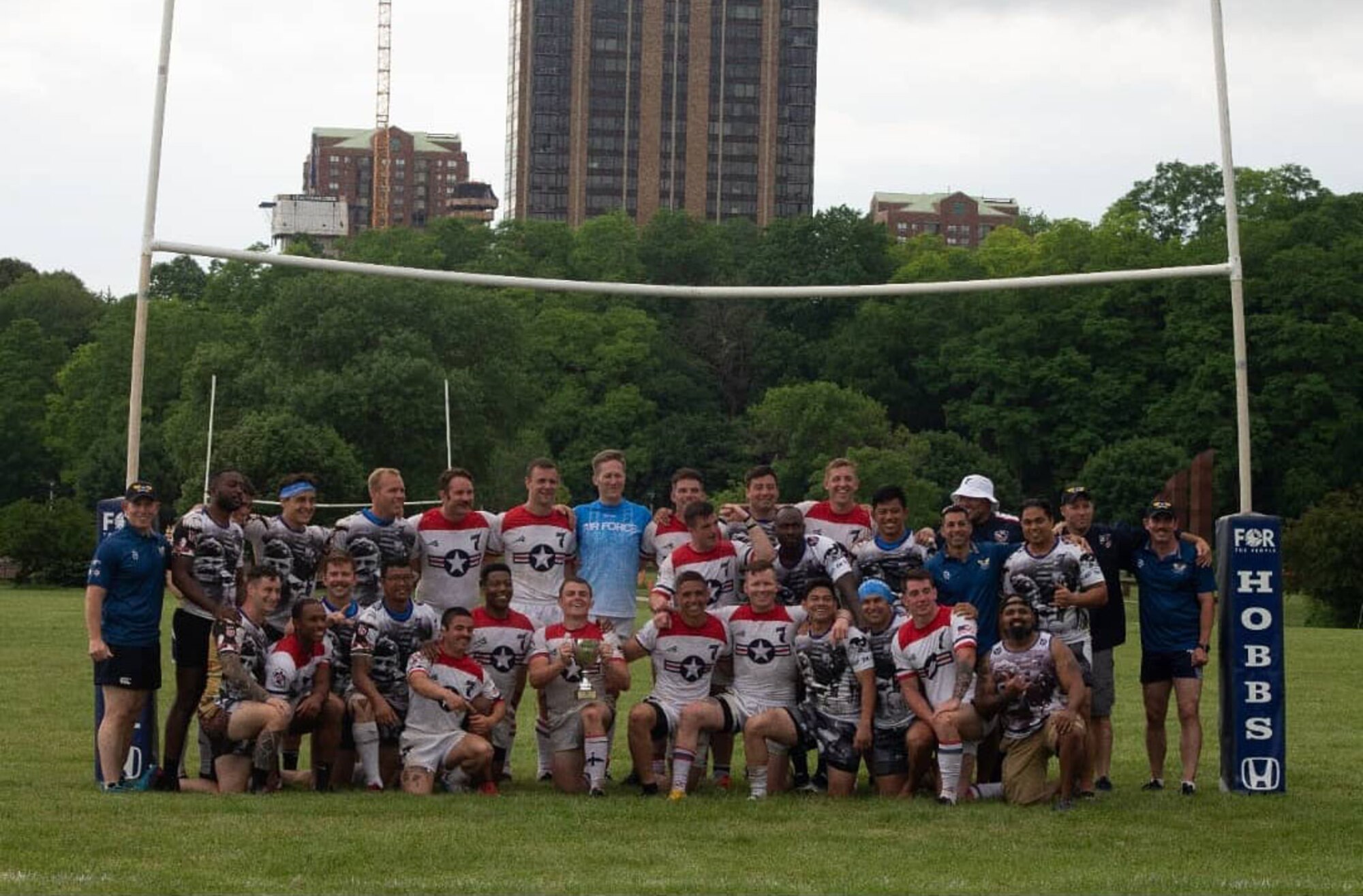 A team of rugby players stand together in front of goal.