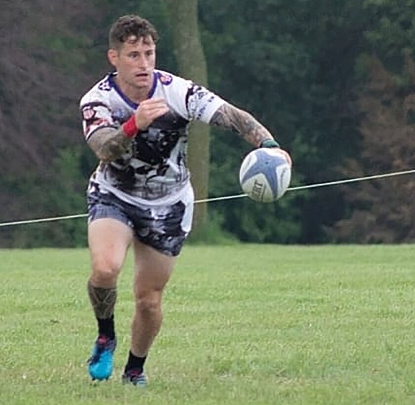 Rugby player runs towards a ball in mid-air.