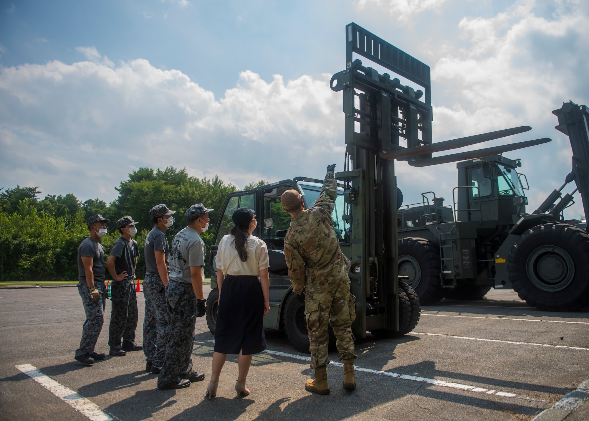 JASDF members watches as USAF members display different parts and actions of a forklift.