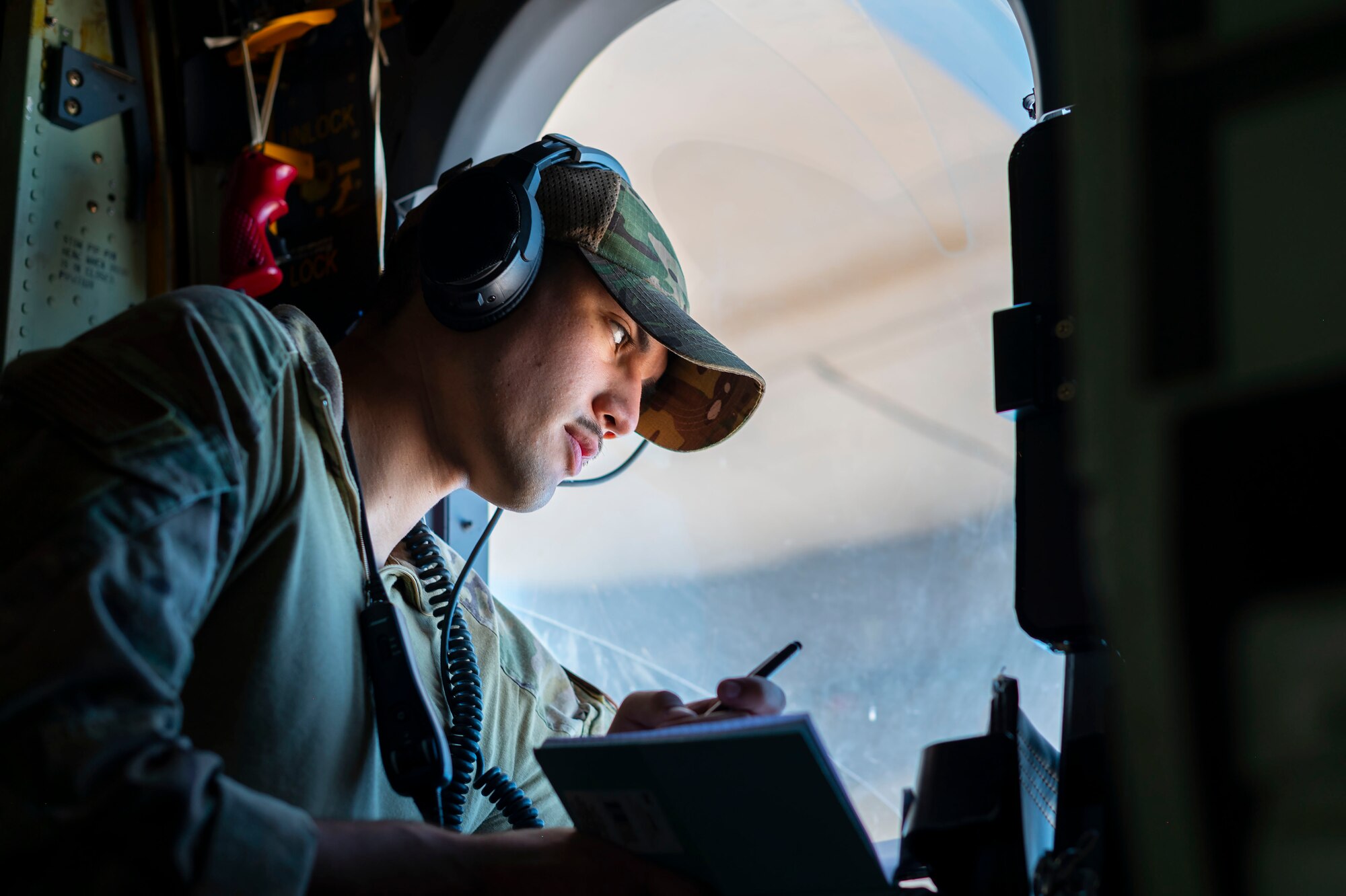 A U.S. Airman from the 26th Expeditionary Rescue Squadron looks out the window from an HC-130J Combat King II during an exercise July 28, 2021, at an undisclosed location somewhere in Southwest Asia. The 26th ERQS stands alert for the U.S. Central Command area of responsibility, providing tanker capability for the associated HH-60G Pave Hawk helicopters and can also provide a forward refueling point in austere locations. (U.S. Air Force photo by Senior Airman Karla Parra)