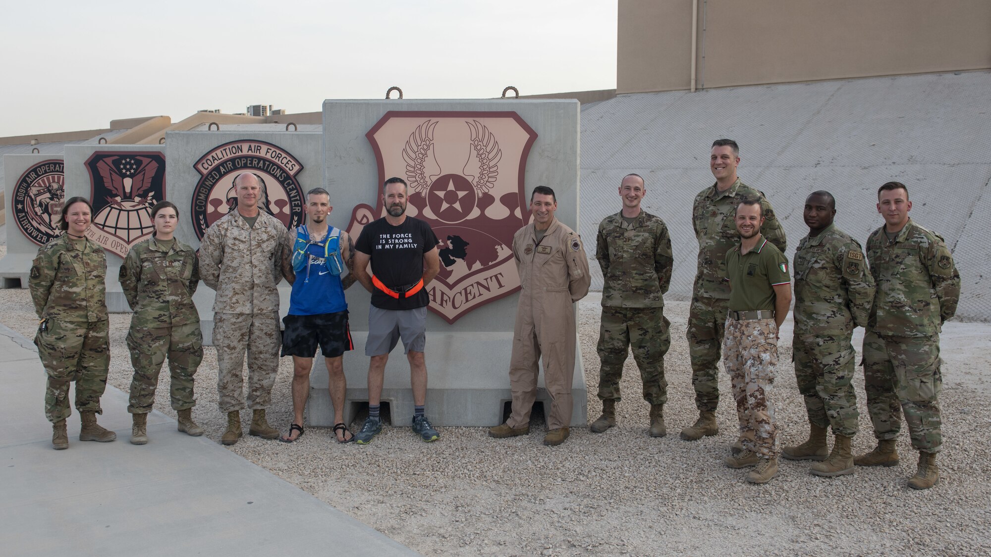 Patrick Buzzard, AFCENT Information Protection director, center left, and Air Forces Central forward staff members stand for a photo at the Combined Air Operations Center, Al Udeid Air Base, Qatar, July 30, 2021. Buzzard ran 51 miles for his 51st birthday with the help of 13 members from the CAOC. (U.S. Air Force photo illustration by Tech. Sgt. Dylan Nuckolls)