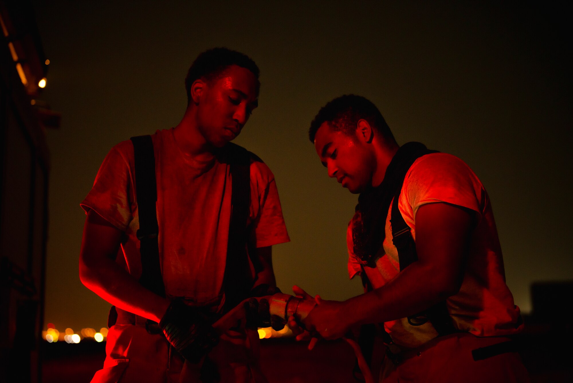 Airman 1st Class Kenyatta Hinton-Pope and Airman 1st Class Matthew Bendorf, 379th Expeditionary Civil Engineer Squadron firefighters, connect a hose during a live-fire training exercise August 10, 2021, at Al Udeid Air Base, Qatar.