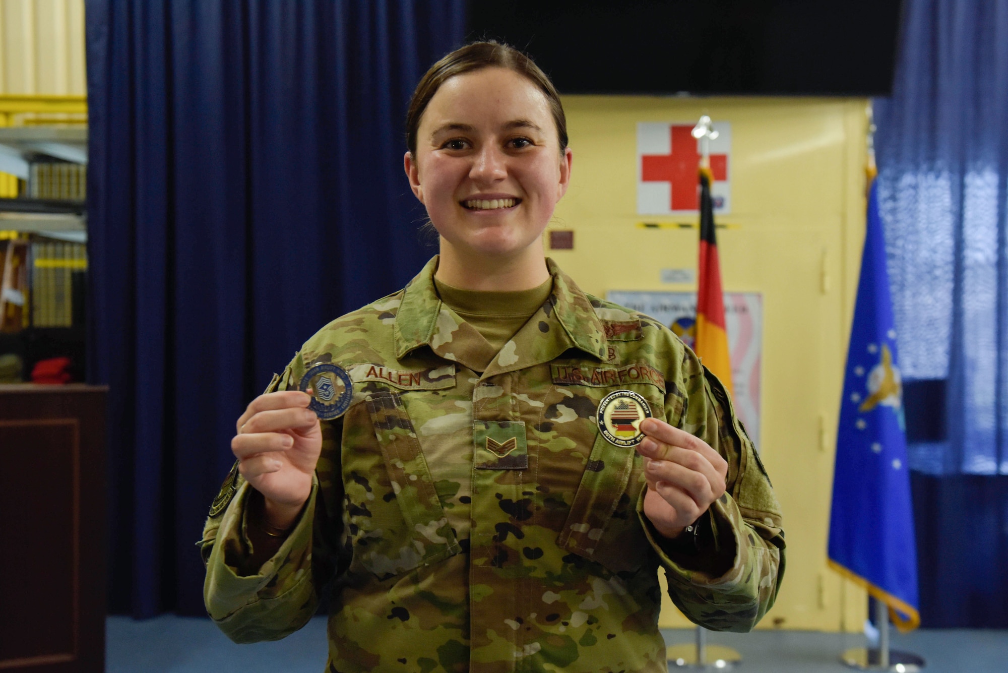 Senior Airman Audrey Allen holds up two coins she earned for being selected Airlifter of the Week