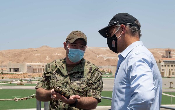 Fire Controlman 1st Class Jonathan Davis, left, shows U.S. Ambassador to Egypt, Jonathan R. Cohen, 20mm close-in weapon system shell casings aboard guided-missile cruiser USS Monterey (CG 61).