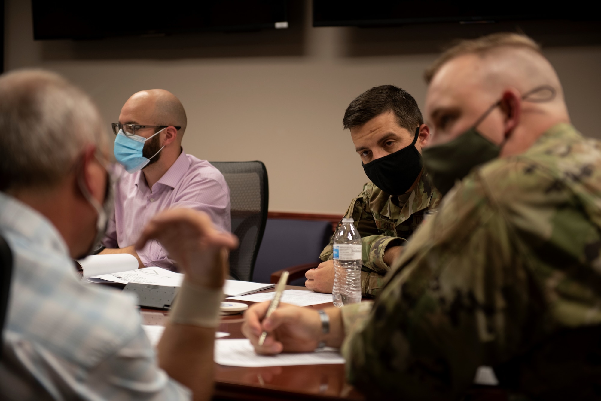 Col. David Wilson, civilian government employees, military members and prospective contractors sit around a table discussing capabilities for an upcoming project.