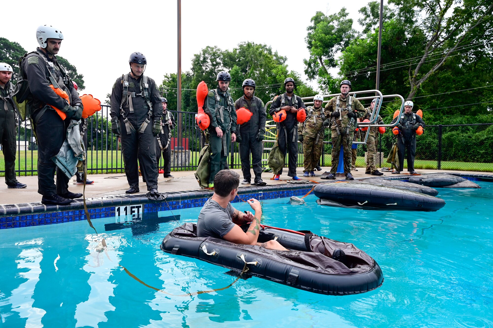 An instructor directs students from a raft during water survival training.