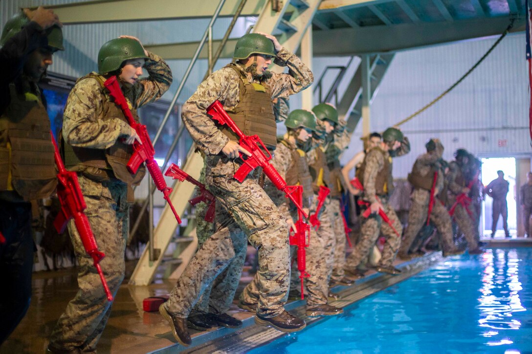 Marines stand at the edge of a pool preparing to step in.