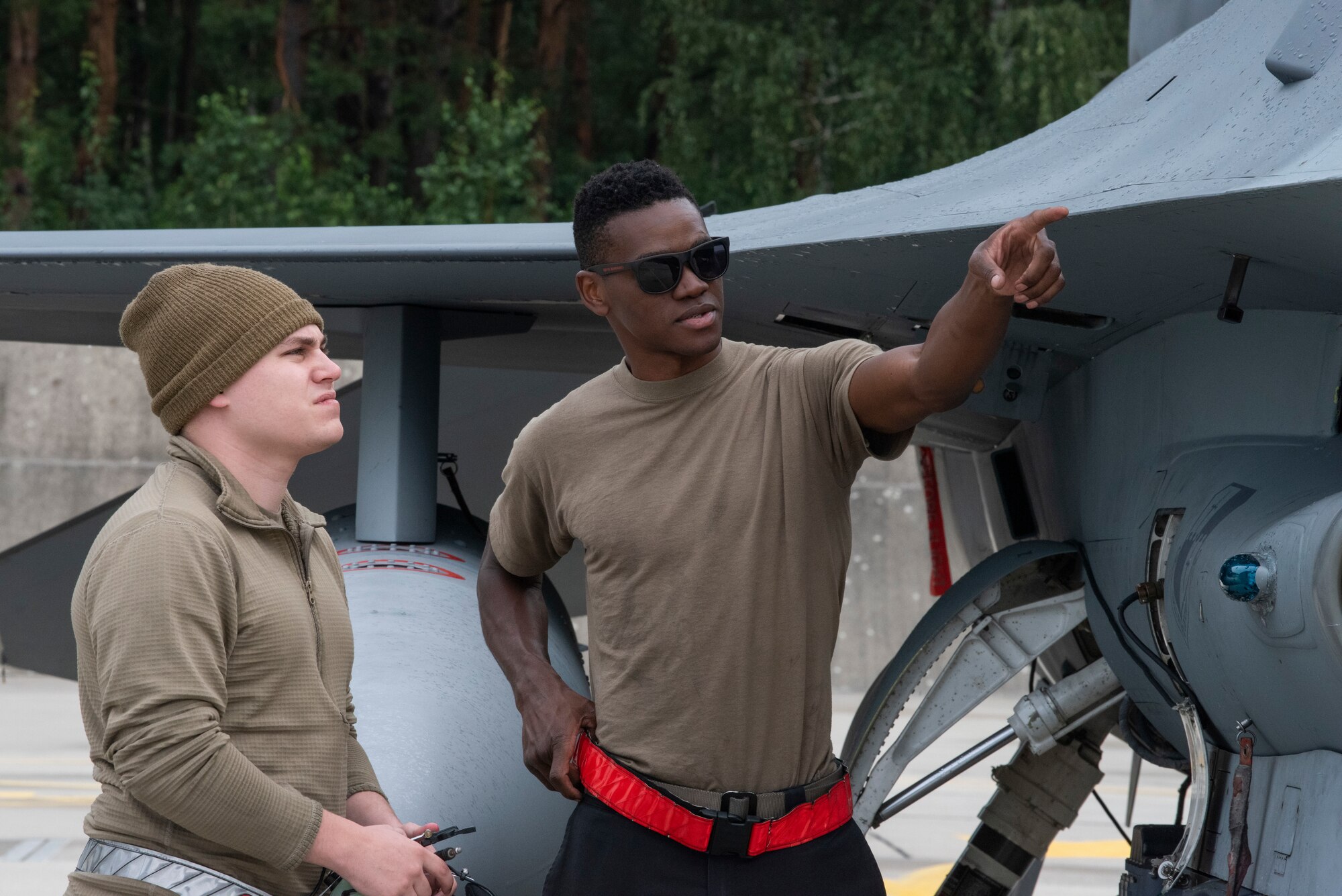 U.S. Air Force Airman 1st Class Samuel Brown, 480th Expeditionary Fighter Squadron crew chief (right), discusses the launch process of a U.S. Air Force F-16 Fighting Falcon with U.S. Air Force Staff Sgt. Richard Juillerat, 480th EFS aircraft fuels system journeyman at Łask Air Base, Poland, August 4, 2021. The Airmen participated in a training program that allows Airmen to shadow a dedicated crew chief during the launch process of an F-16 Fighting Falcon. (U.S. Air Force photo by Tech. Sgt. Anthony Plyler)