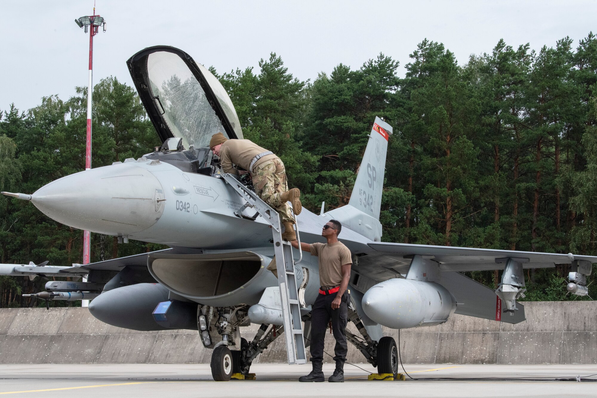 U.S. Air Force Staff Sgt. Richard Juillerat, 480th Expeditionary Fighter Squadron aircraft fuels system journeyman, peers into a U.S. Air Force F-16 Fighting Falcon as U.S. Air Force Airman 1st Class Samuel Brown, 480th EFS crew chief, explains the role of a dedicated crew chief at Łask Air Base, Poland, August 4, 2021. U.S. Air Force F-16 Fighting Falcons and support personnel are in Poland to participate in Aviation Detachment Rotation 21.3. (U.S. Air Force photo by Tech. Sgt. Anthony Plyler)