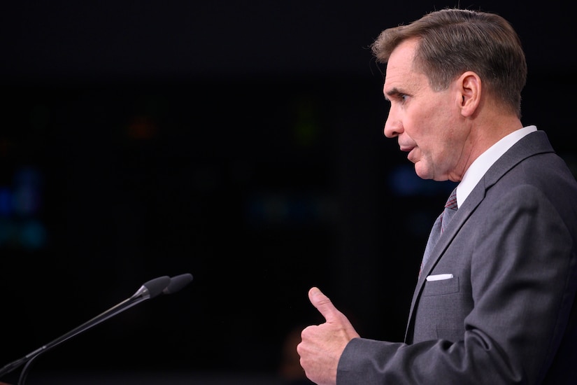 Pentagon Press Secretary John F. Kirby stands in front of a microphone.