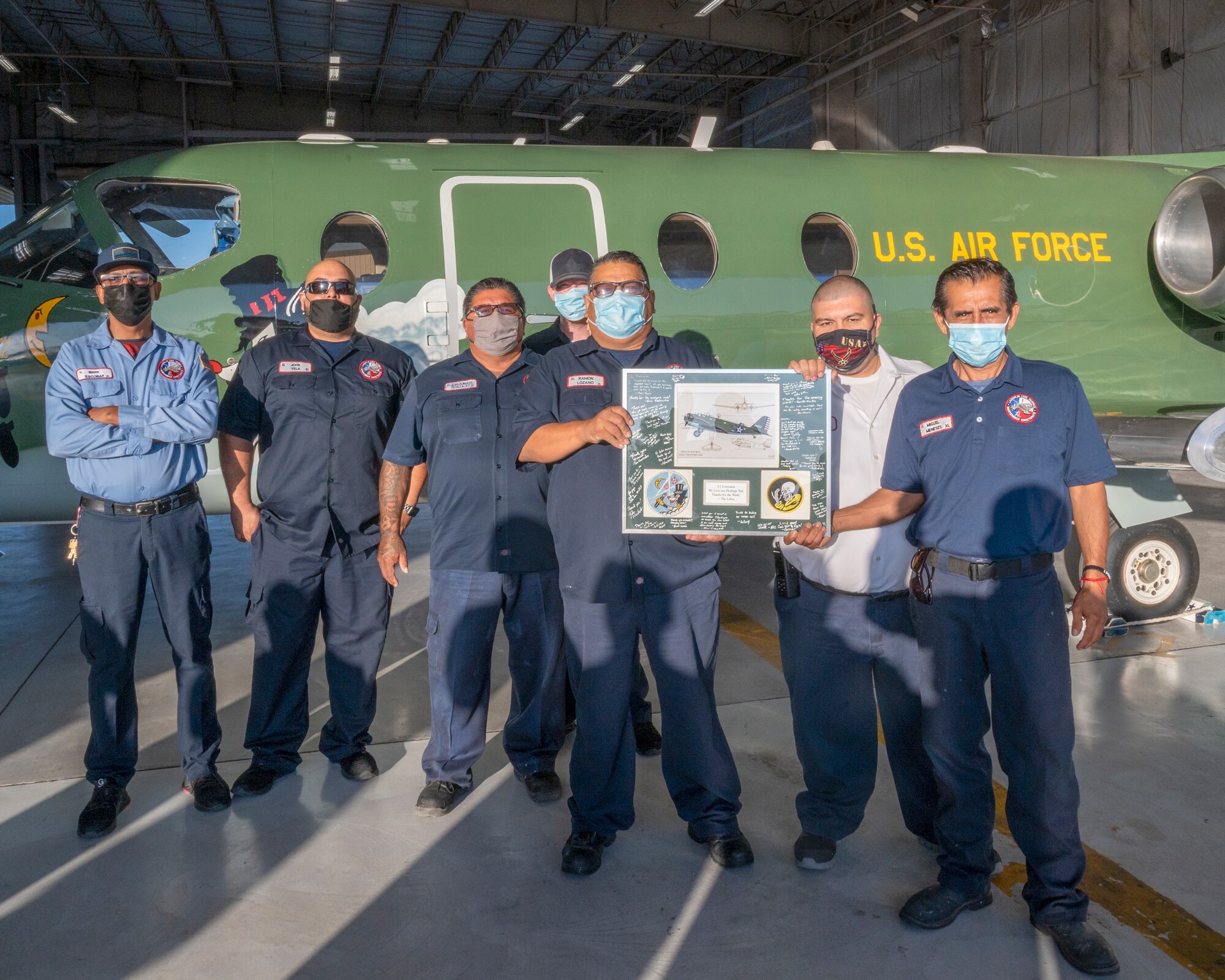 Maintainers from the corrosion shop at Laughlin Air Force Base, Texas, pose with the plaque given to them for their work with the heritage tail on August 13, 2021. The Douglas B-18 “Bolo” paint scheme dates back to World War II and honors a rich Air Force heritage. (U.S. Air Force Photo by Senior Airman Nicholas Larsen)