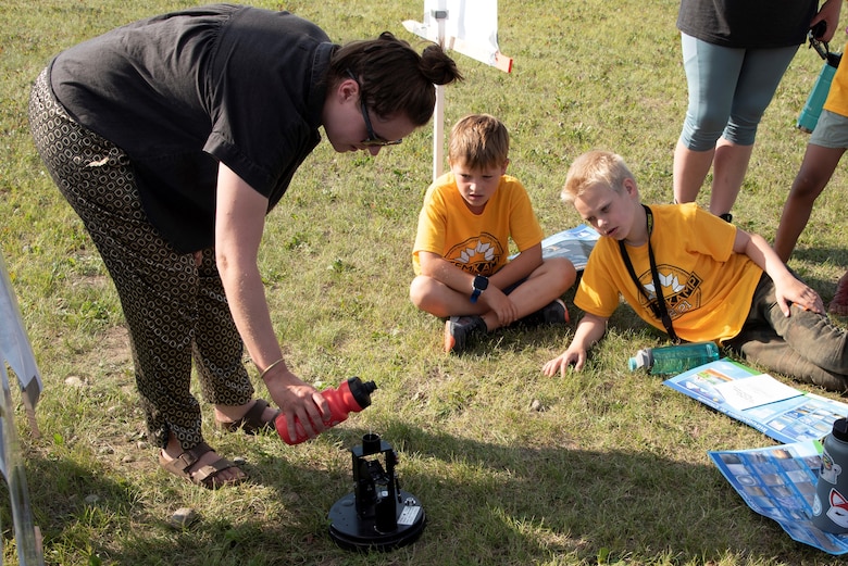 Students watch Lauren Oliver, hydraulics and hydrology engineer with the U.S. Army Corps of Engineers – Alaska District, demonstrate a tipping bucket rainwater gauge on Aug. 5 at the Chena River Lakes Flood Control Project near North Pole, Alaska.