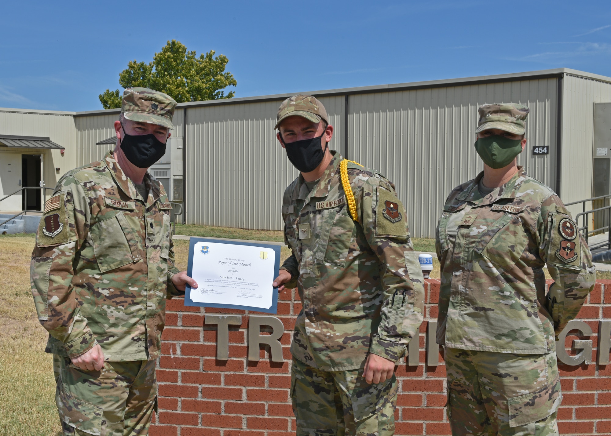 U.S. Air Force Lt. Col. James Freeman, 17th Training Group deputy commander, and Senior Master Sgt. Heather Celano, 313th Training Squadron superintendent, present Airman Jachin Lamey, 312th Training Squadron student, the 17th TRG Rope of the Month award for July 2021, on Goodfellow Air Force Base, Texas, August 13, 2021. Military Training Leaders present different ropes to Airmen who display exceptional qualities to lead their peers. Lamey was recognized for his hard work and dedication in his rope duties. (U.S. Air Force photo by Senior Airman Ashley Thrash)