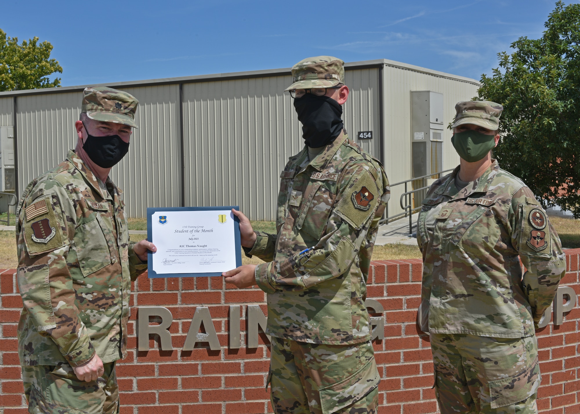 U.S. Air Force Lt. Col. James Freeman, 17th Training Group deputy commander, and Senior Master Sgt. Heather Celano, 313th Training Squadron superintendent, present Airman 1st Class Thomas Vaught, 315th Training Squadron student, the 17th TRG Student of the Month award for July 2021, on Goodfellow Air Force Base, Texas, August 13, 2021. Vaught exhibited his dedication to his squadron and the training he received at Goodfellow. (U.S. Air Force photo by Senior Airman Ashley Thrash)