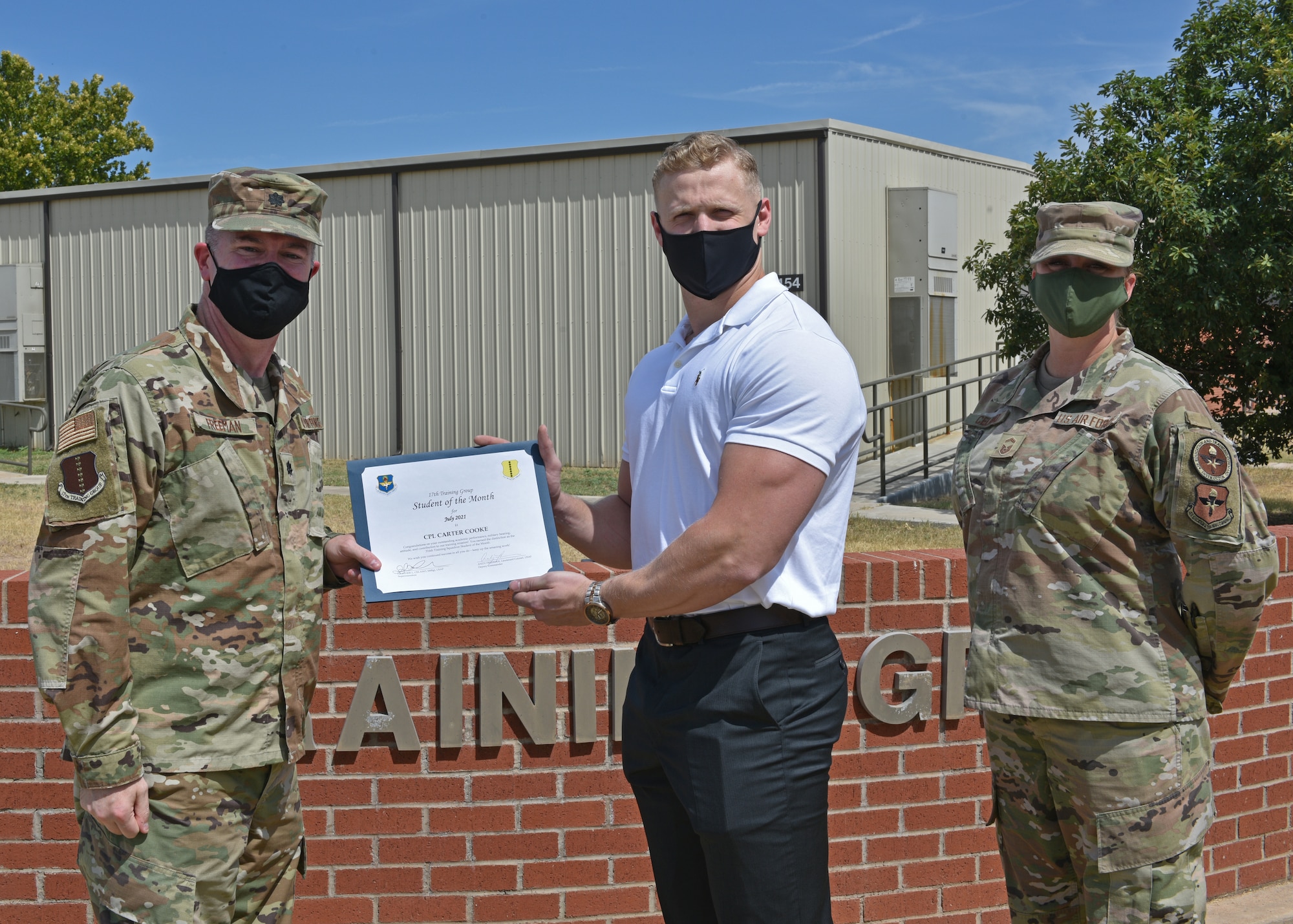 U.S. Air Force Lt. Col. James Freeman, 17th Training Group deputy commander, and Senior Master Sgt. Heather Celano, 313th Training Squadron superintendent, present U.S. Marine Corps Cpl. Carter Cooke, 316th Training Squadron student, the 17th TRG Student of the Month award for July 2021, on Goodfellow Air Force Base, Texas, August 13, 2021. The 316th TRS is responsible for training, developing, and inspiring intelligence, surveillance, and reconnaissance cryptologic leaders. (U.S. Air Force photo by Senior Airman Ashley Thrash)