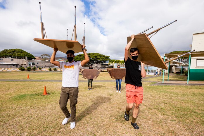 U.S. Marines with Headquarters Battalion, Marine Corps Base Hawaii, carry desks to another classroom during a volunteer event at Kailua Elementary School, Hawaii, July 30, 2021. MCBH’s most important resource is people, partnering with and supporting the local community is among the installation’s top priorities. (U.S. Marine Corps photo by Lance Cpl. Samantha Sanchez)