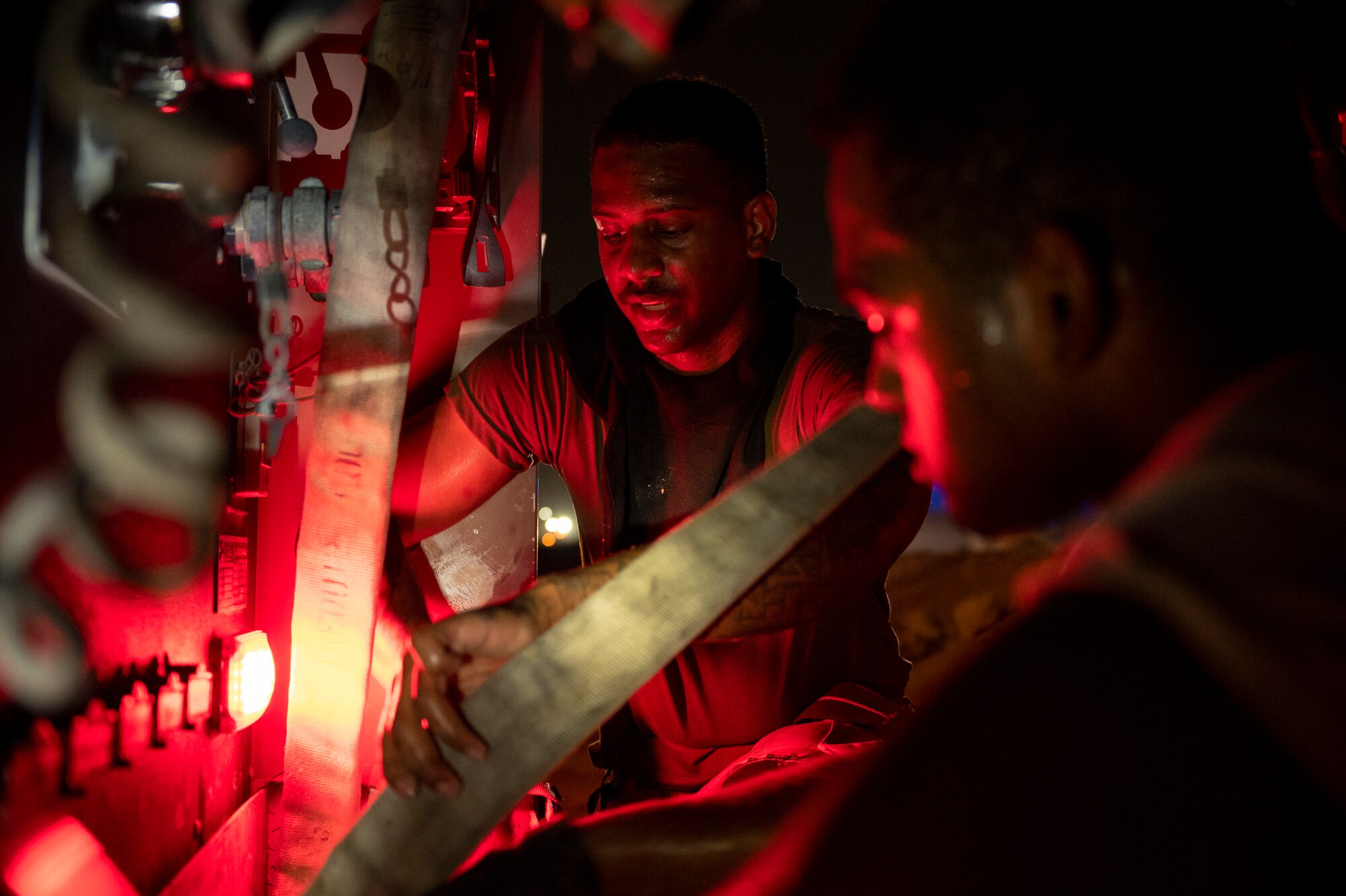 Airman 1st Class Javon Coleman and Airman 1st Class Matthew Bendorf, 379th Expeditionary Civil Engineer Squadron firefighters, put away a firehose following live-fire training, August 10, 2021, at Al Udeid Air Base, Qatar.