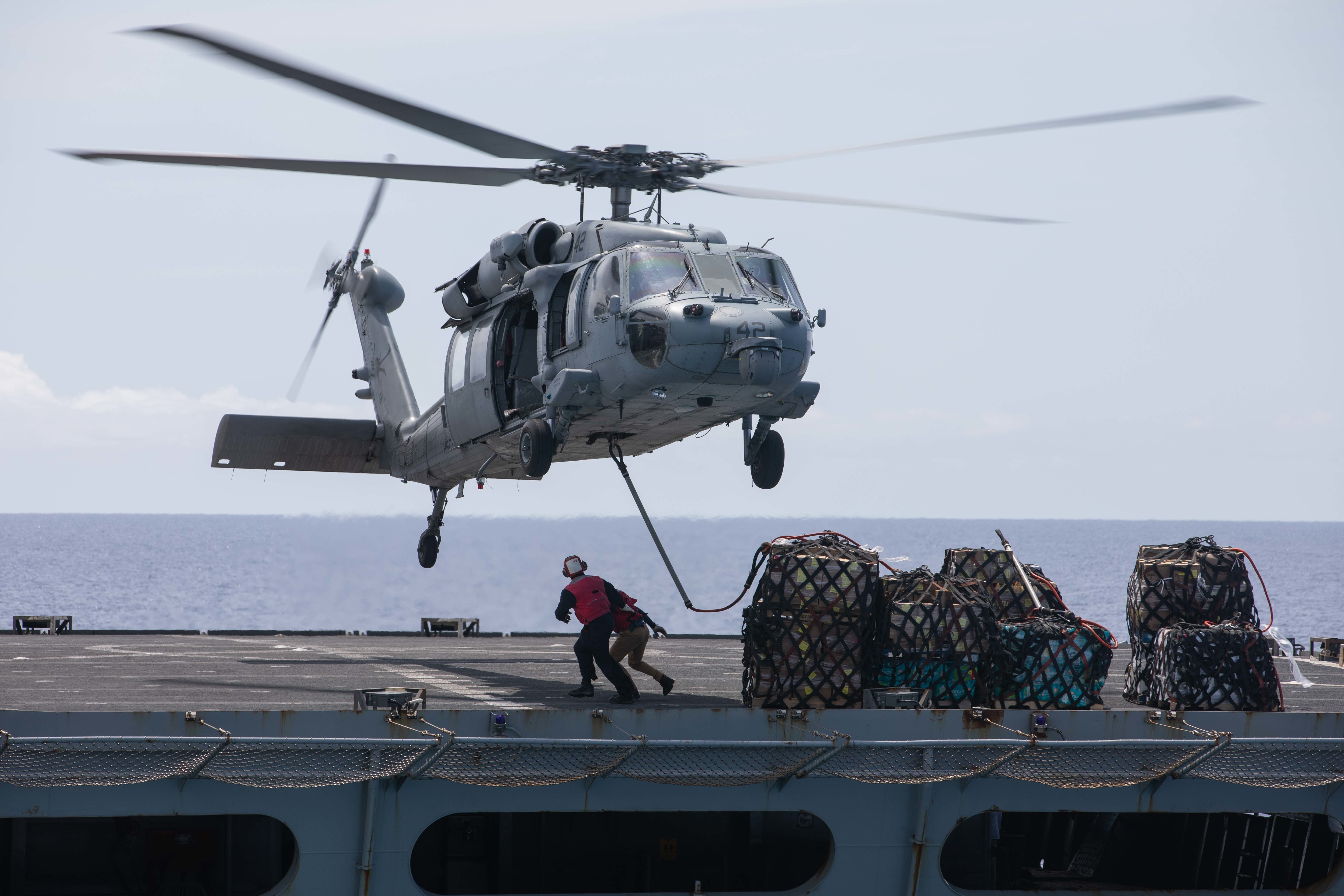 ATLANTIC OCEAN (Aug. 9, 2021) An MH-60S Sea Hawk helicopter attached to Helicopter Sea Combat Squadron (HSC) 28 transfers supplies from the fast combat support ship USNS Arctic (T-AOE 8) to the Wasp-class amphibious assault ship USS Kearsarge (LHD 3).