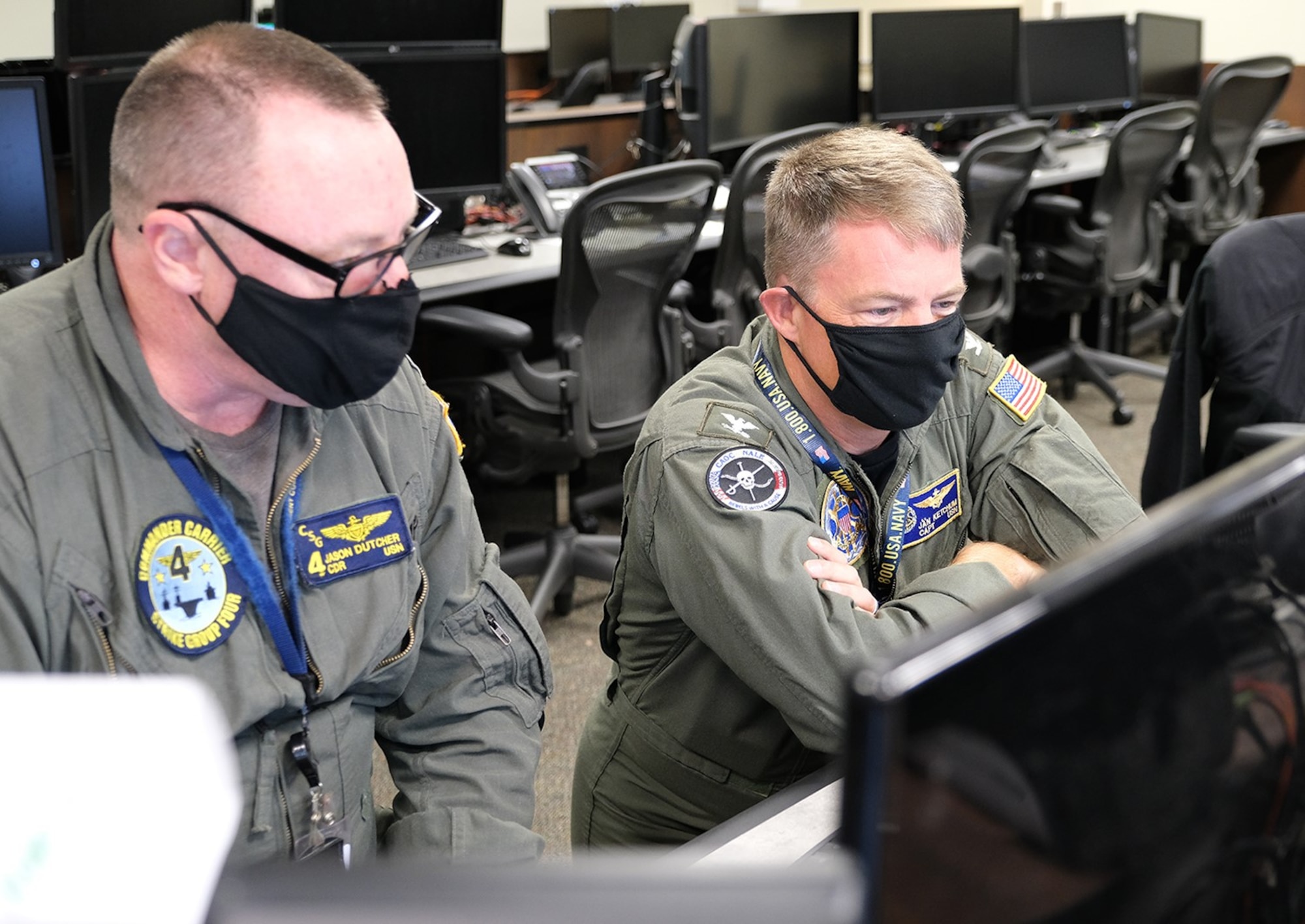 photo of two U.S. Navy members sitting looking at computer monitors.