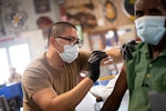 Navy Petty Officer 3rd Class Jemuel Macabali, from San Diego, Calif., gives the COVID-19 vaccine to staff at Camp Lemonnier, in Djibouti, Aug. 13, 2021. Camp Lemonnier, Djibouti, serves as an expeditionary base for U.S. military forces providing support to ships, aircraft and personnel that ensure security throughout Europe, Africa and Southwest Asia.
