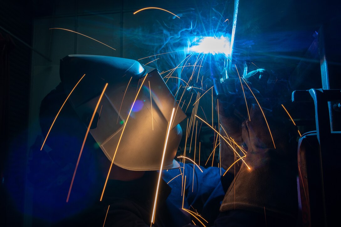 Aircraft metals technician welds a frame together