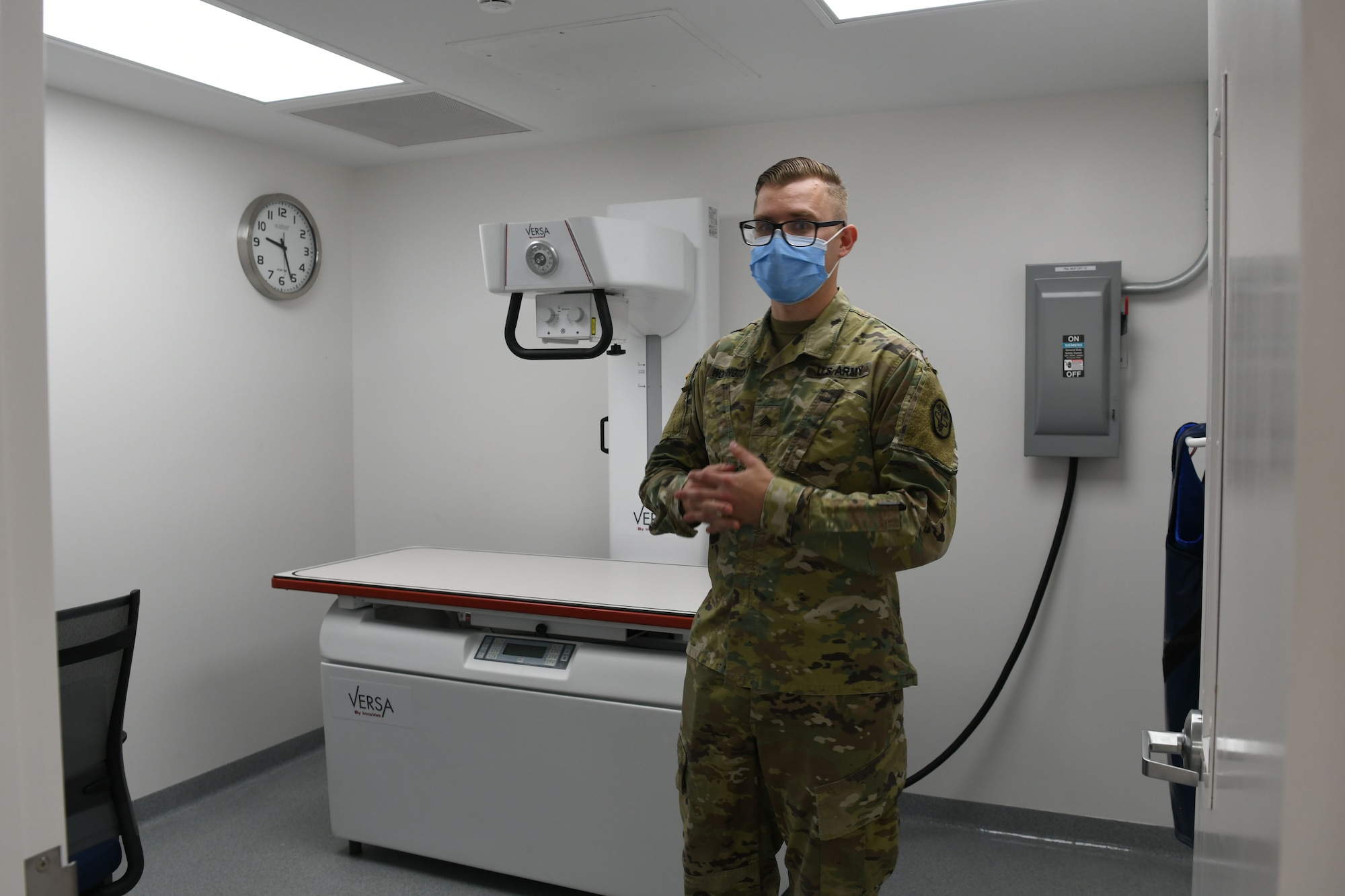 Photo shows male Airman standing in front of exam table while speaking.
