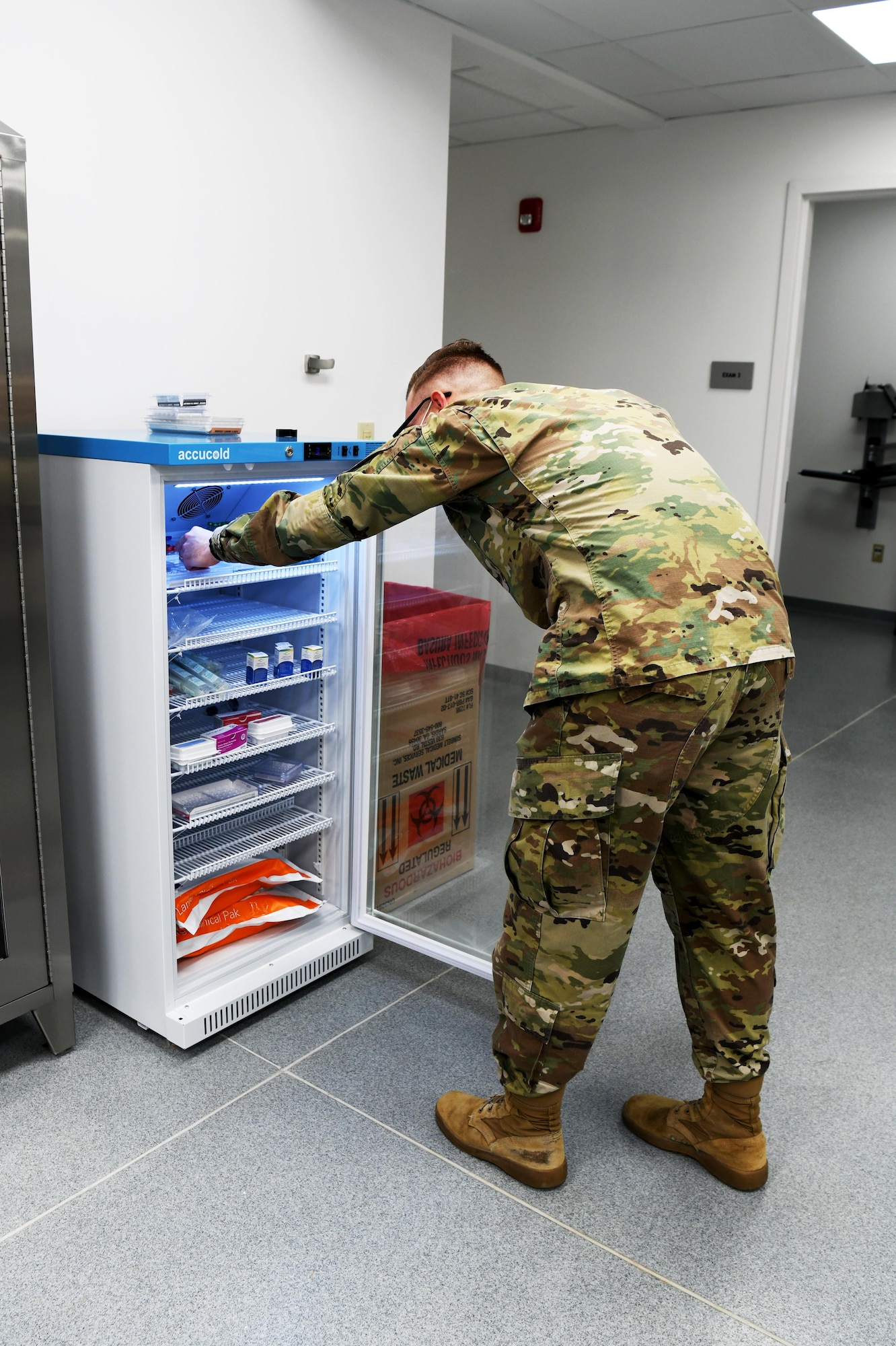 Photo shows male Airmen looking into refrigerator with medical supplies.