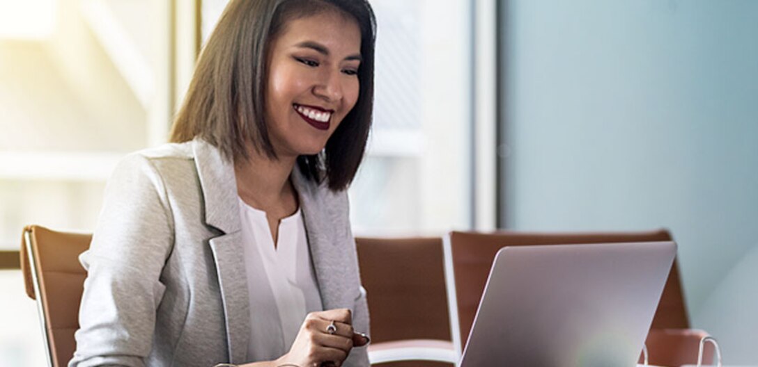 Lady smiling while looking at her computer.