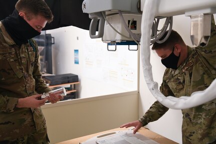 Airman 1st Class Troy Thibodeau, Biomedical Equipment Technician program student, left, and Staff Sgt. Austin Jur, instructor, right, examine medical equipment at the Medical Education and Training Campus.