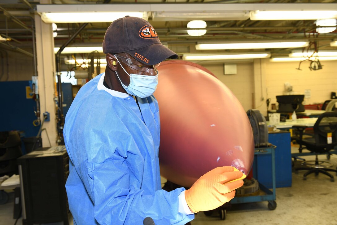 man apply putty to aircraft nose cone
