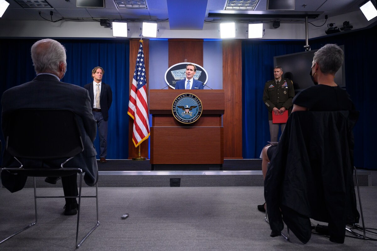 Three men stand in front of an audience.