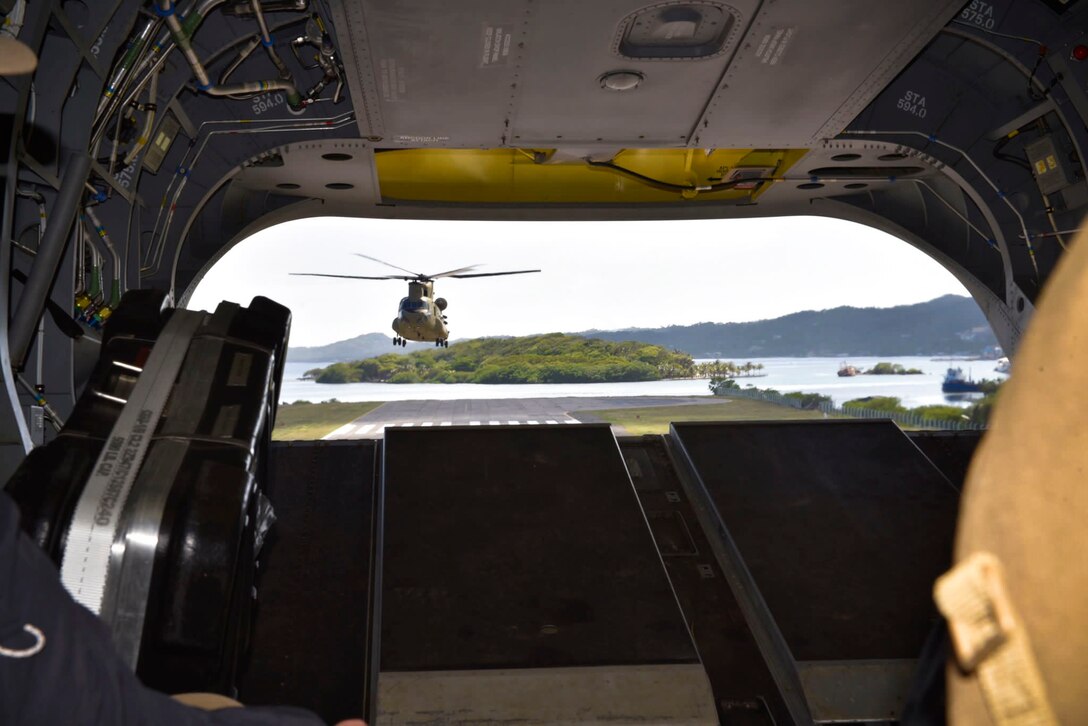 A helicopter lands as seen through the back hatch of another helicopter.