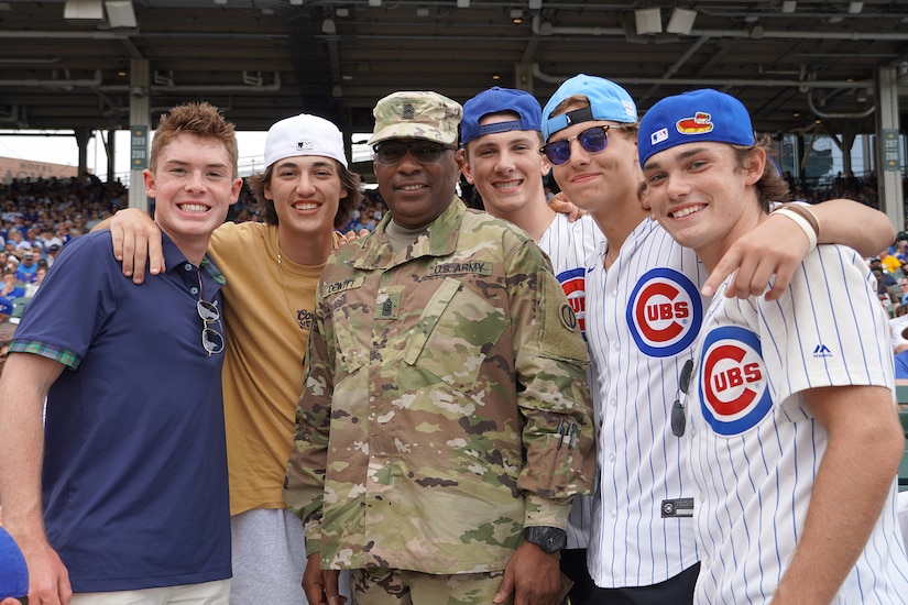 U.S. Army Reserve Command Sgt. Maj Theodore Dewitt, center, pauses for a photo with game spectators after receiving an honor for his service during the Chicago Cubs home game, at Wrigley Field in Chicago, August 12, 2021.