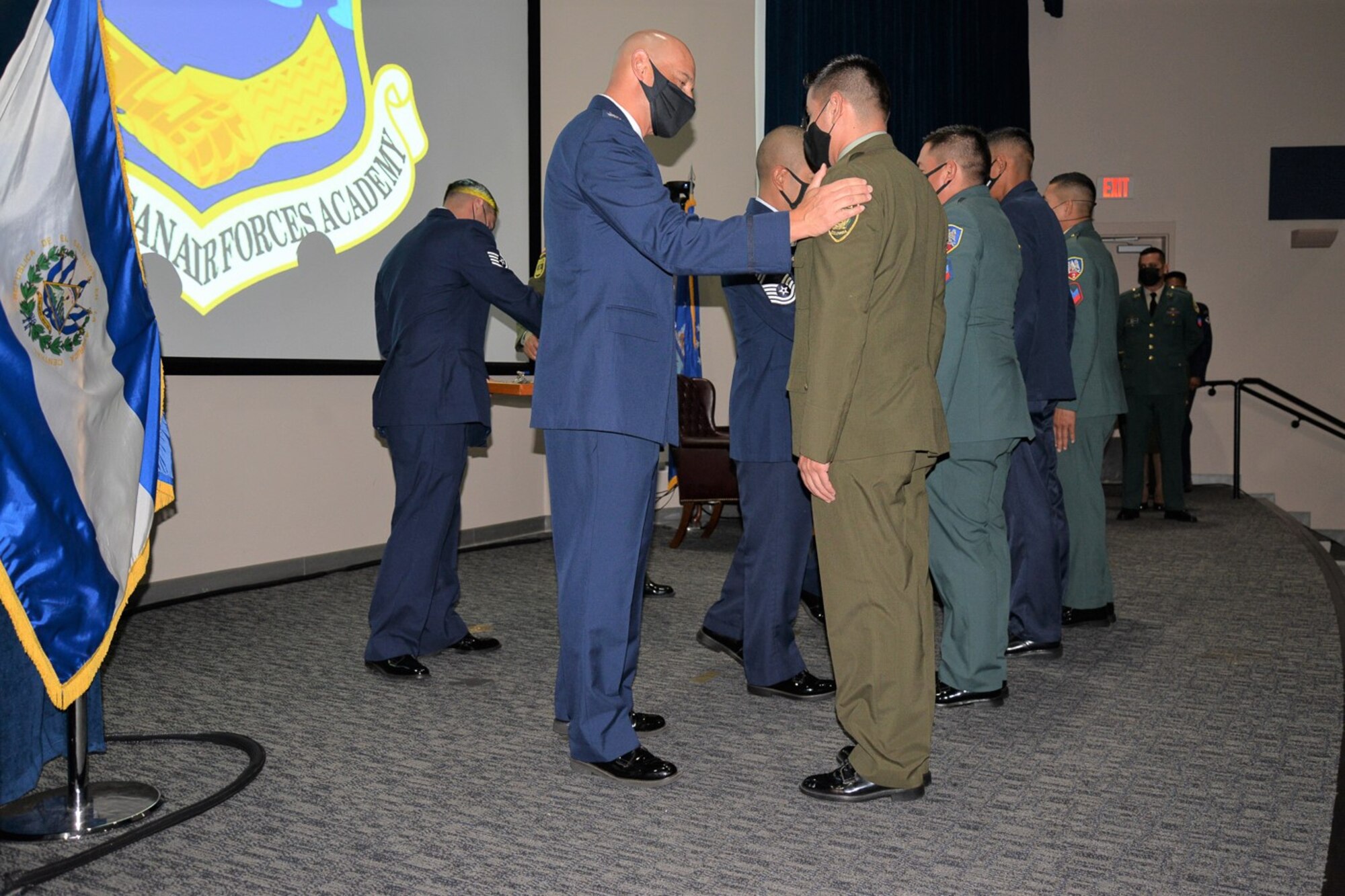 Military members from partner nations are congratulated by IAAFA leadership on stage.