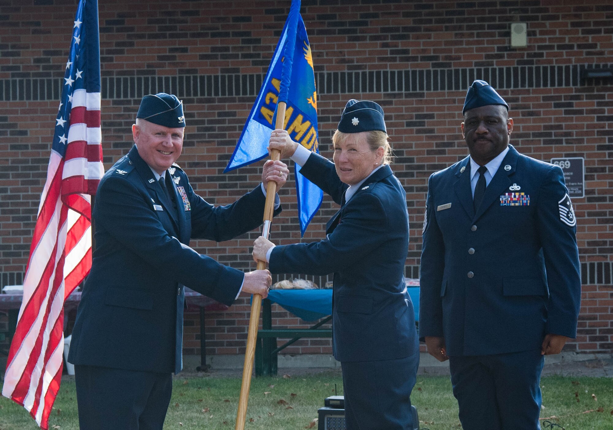 Col. Thomas Pemberton, 434th Air Refueling Wing commander, passes the guidon to Lt. Col. Kelli Bermudez, 434th Aerospace Medicine Squadron commander, during an assumption of command ceremony at Grissom Air Reserve Base, Ind., Aug. 8, 2021.