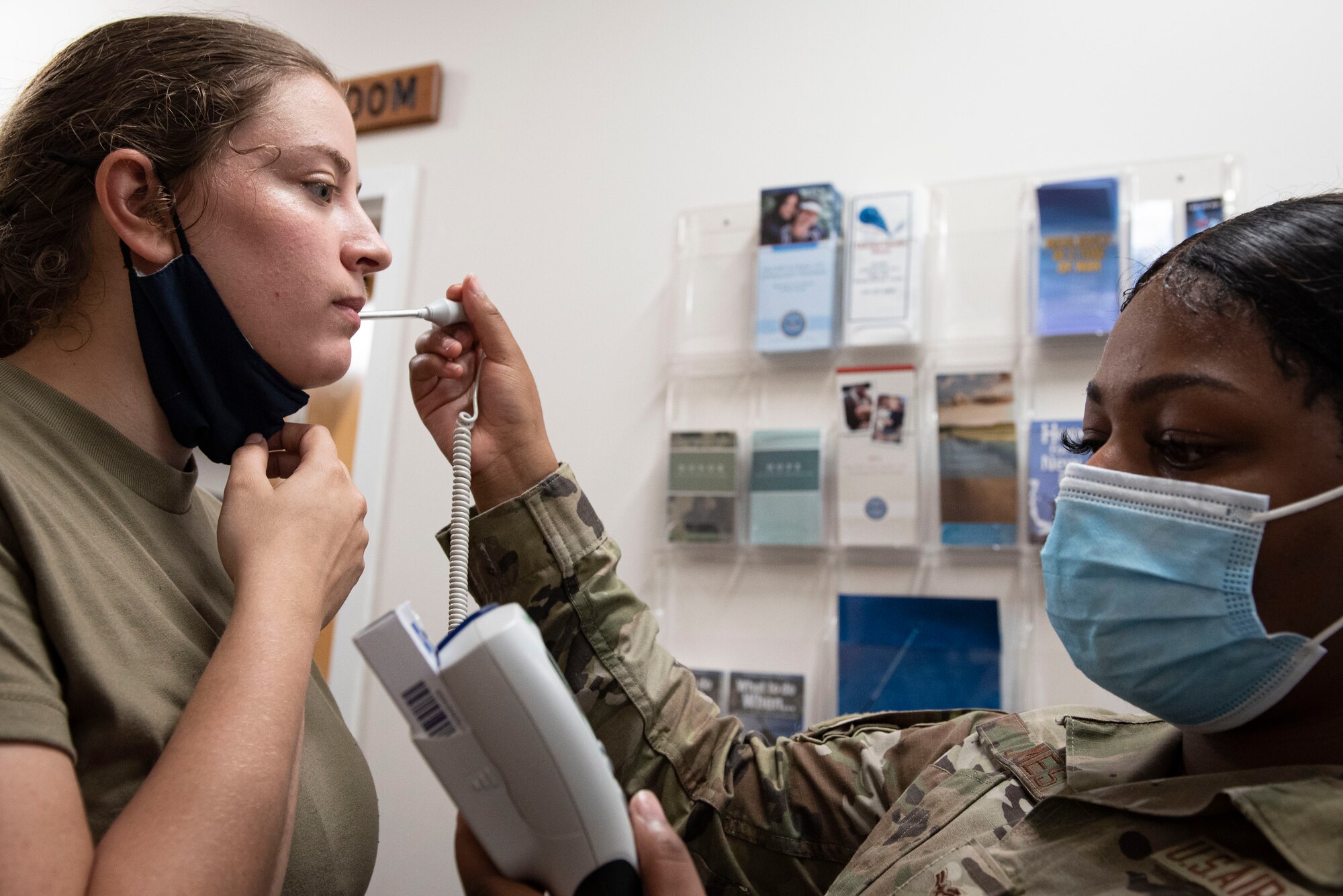 A photo of an Airman getting their temperature taken.