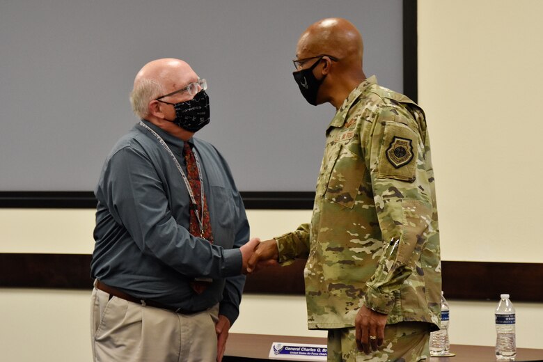 Russ Foos, Air Force Operational Test and Evaluation Center training chief, receives a coin of excellence from Air Force Chief of Staff Gen. CQ Brown, Jr., during CSAF’s visit to the center at Kirtland Air Force Base, N.M., Aug. 12, 2021. Brown visited the course where both Air and Space Force students are taught how to plan, execute and report operational testing throughout the acquisition of combat capability.