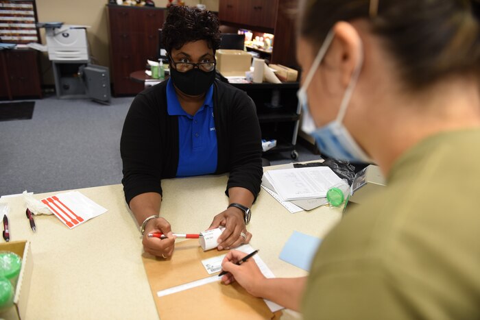 Photo shows two women sitting at table going over paperwork.