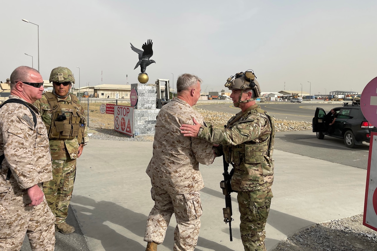 A Marine and a sailor shake hands outside an airport.