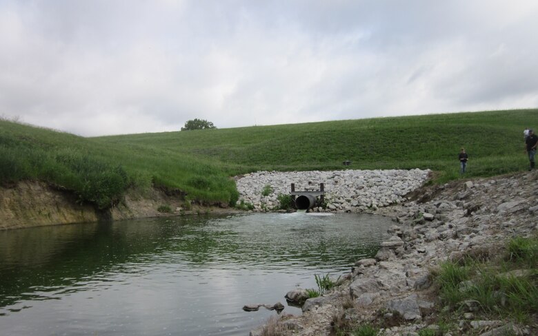 Salt Creek 8 (Wagon Train) Plunge Pool near Lincoln, Nebraska looking toward the dam from the downstream outlet channel. The U.S. Army Corps of Engineers will repair both the left and right side of the plunge pool. Note on the left side of the picture there is no riprap and undersized rip rap on the right side. Both the left and right sides of the pool will be repaired. The pipe is the conduit pipe that outlets the reservoir water into the plunge pool, May 25, 2021.