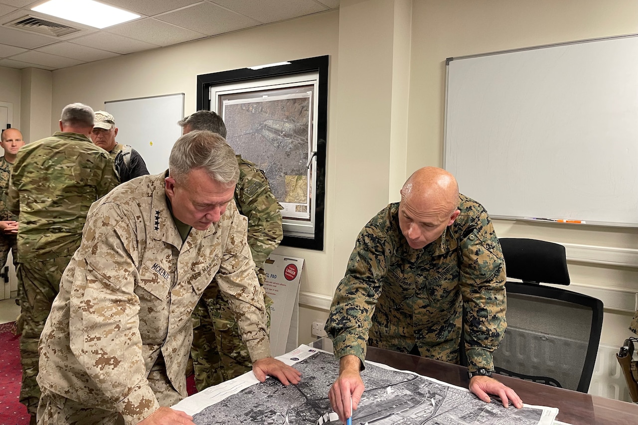 Two Marines look at a map.