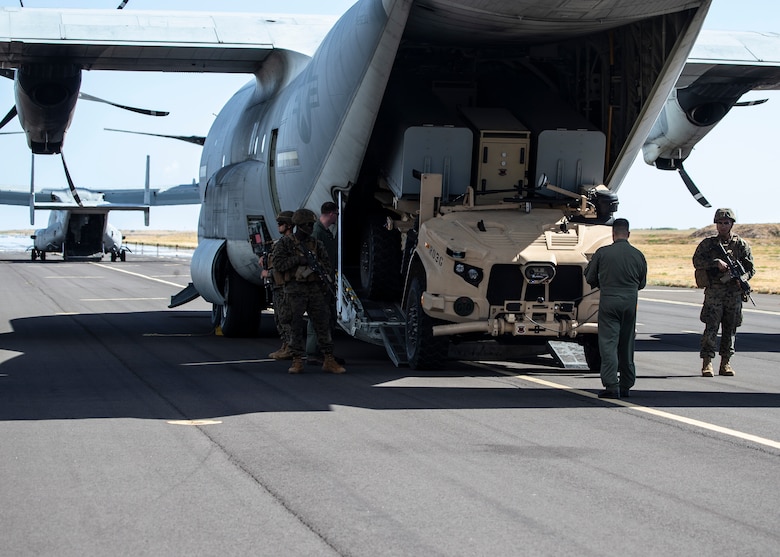 Artillery Marines from 1st Battalion, 12th Marines provide security as a Marine KC-130J loadmaster deploys a Navy Marine Expeditionary Ship Interdiction System launcher aboard Pacific Missile Range Facility Barking Sands, Hawaii, Aug. 15, 2021. After striking a naval target ship with two Naval Strike Missiles flying 100 nautical miles, 1/12 rehearsed tactical displacement and relocation. A key component of the Marine Corps’ Force Design 2030, expeditionary advanced base operations include low-signature, dispersed teams of Marines holding a potential adversary’s ships at risk from long-range precision strike weapons, providing sea control and contributing to sea denial in support of the Fleet. The training, part of Large Scale Exercise 2021, allowed Marines to refine support to distributed maritime operations by providing expeditionary advanced base operations and littoral operations in a contested environment.  (U.S. Marine Corps photo by Cpl. Luke Cohen, released)