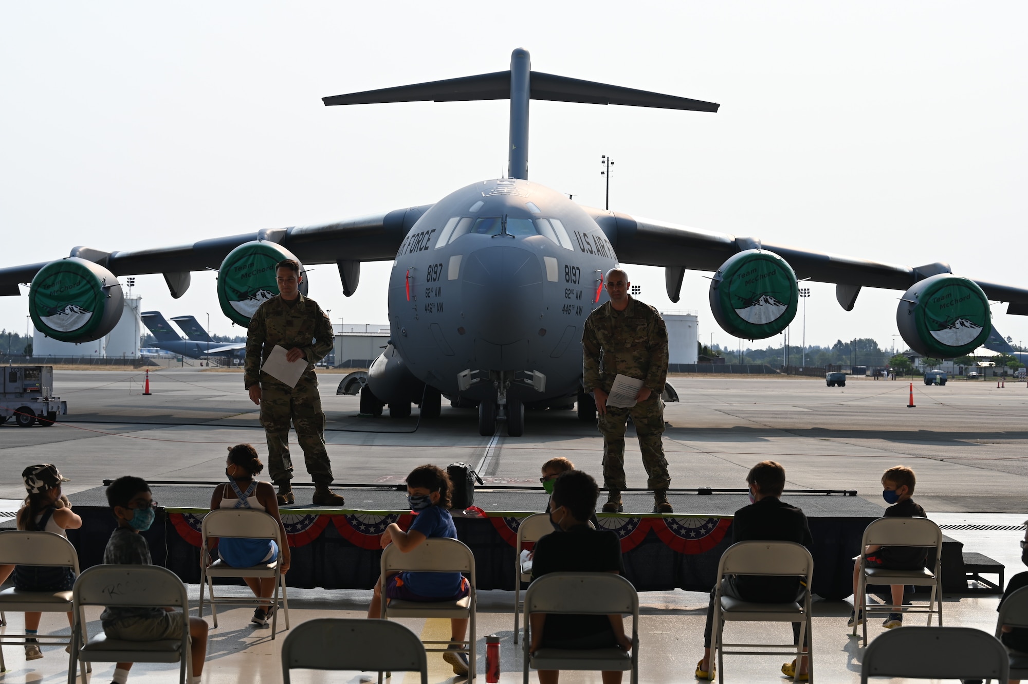 U.S. Air Force Maj. Wesley Ekwall, 62nd Aerial Port Squadron commander, and Senior Master Sgt. James Wall, 62nd APS senior enlisted leader, brief Team McChord children as part of Operation Kids Understanding Deployment Operations (KUDOs) at Joint Base Lewis-McChord, Washington, Aug. 14, 2021. More than 90 children, ages 4 to 14, participated in the mock deployment. (U.S. Air Force photo by Master Sgt. Julius Delos Reyes)