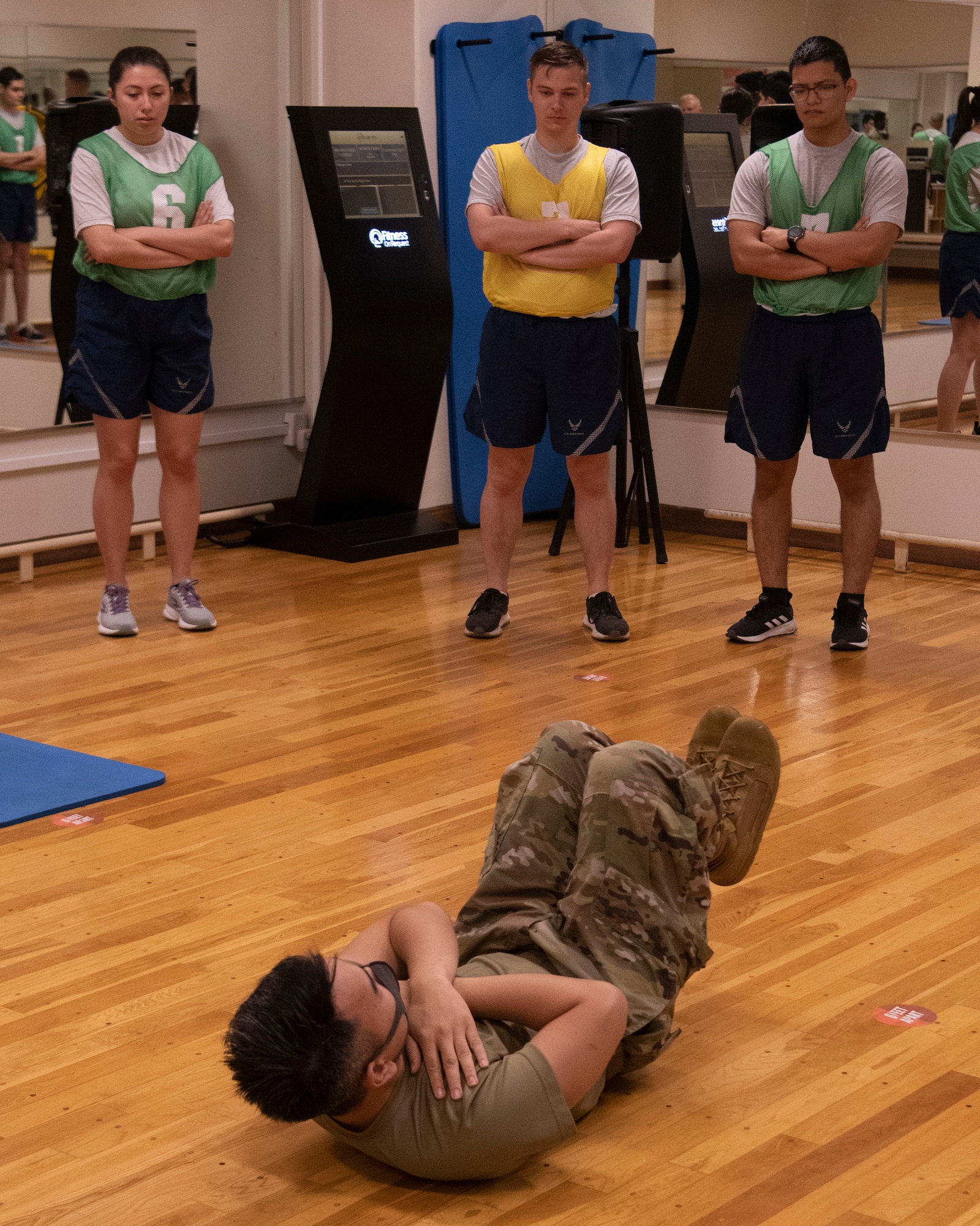 Senior Airman Bryant Solon, 374th Force Support Squadron Fitness Assessment Cell administrator, demonstrates a cross-leg reverse crunch during a mock test at Yokota Air Base, Japan, Aug. 13, 2021. The FAC is evaluating the trial components of the fitness assessment to provide feedback and develop the test before it goes live. (U.S. Air Force photo by Staff Sgt. Braden Anderson)