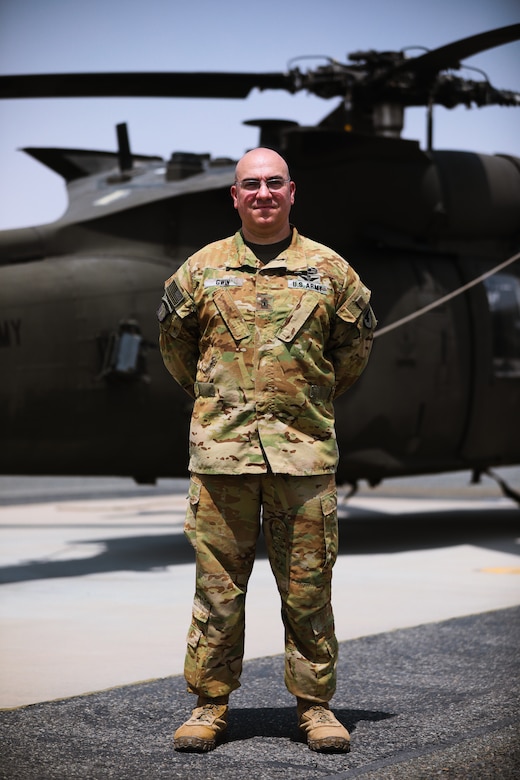 1st Sgt. Matthew Gwin, maintenance noncommissioned officer in charge, 1100th Theater Aviation Support Maintenance Group, stands in front of a UH-60 Blackhawk helicopter at Camp Buehring, Kuwait, July 26, 2021. Gwin provided guidance to the 19 Soldiers from the 82nd Combat Aviation Brigade who deployed to Kuwait to augment the 1100th TASM-G and help alleviate a shortage of aviation contractors due to the COVID-19 pandemic. (U.S. Army photo by Sgt. Jimmie Baker)