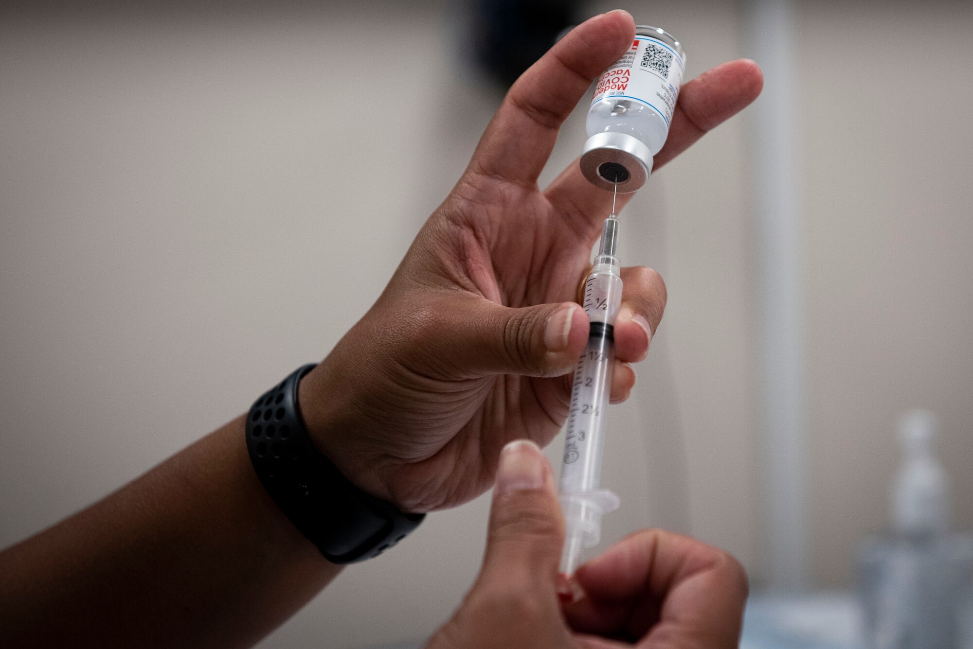 A photo of an Airman filling up a syringe.