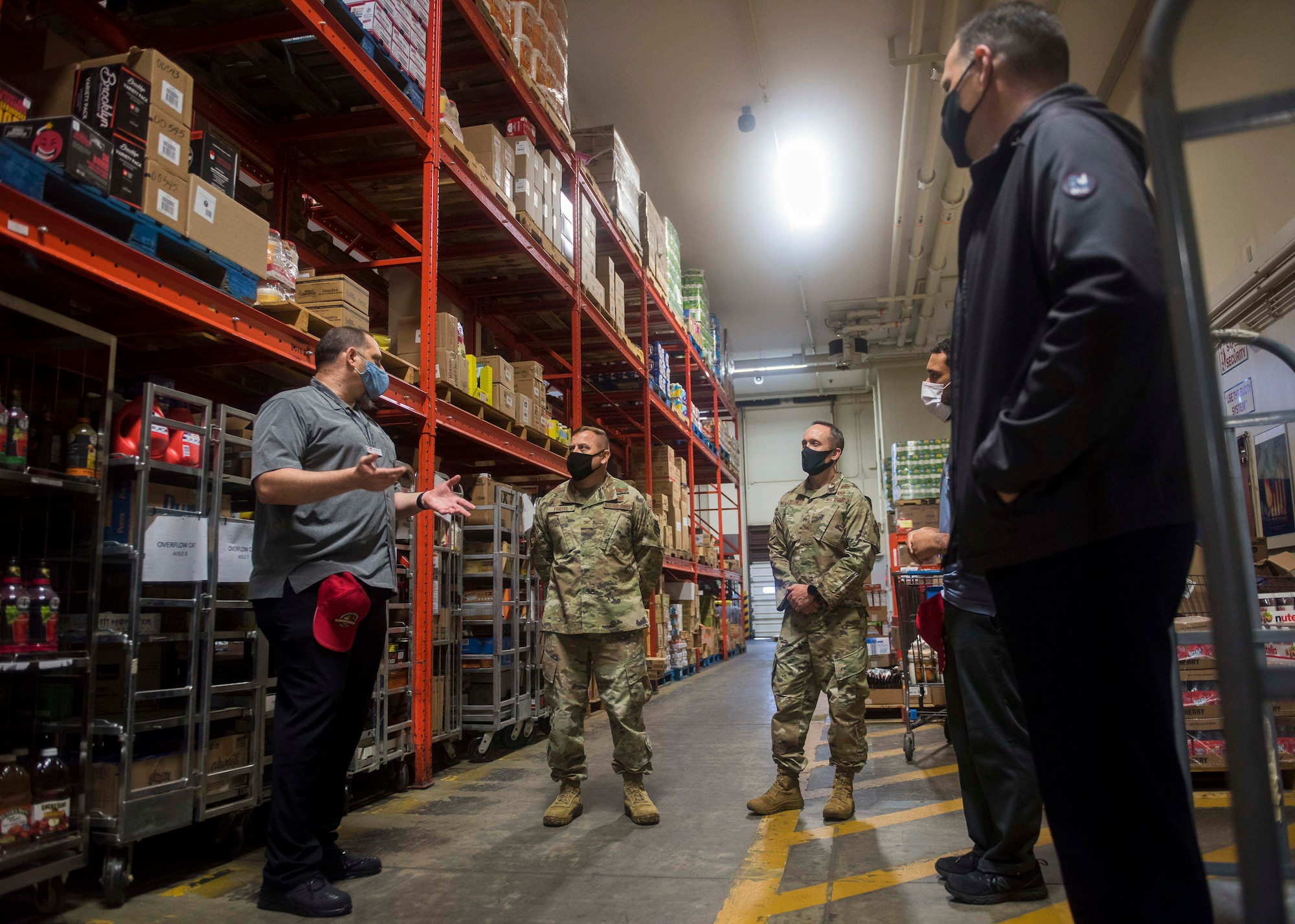 A commissary worker introduces the warehouse to two military members.