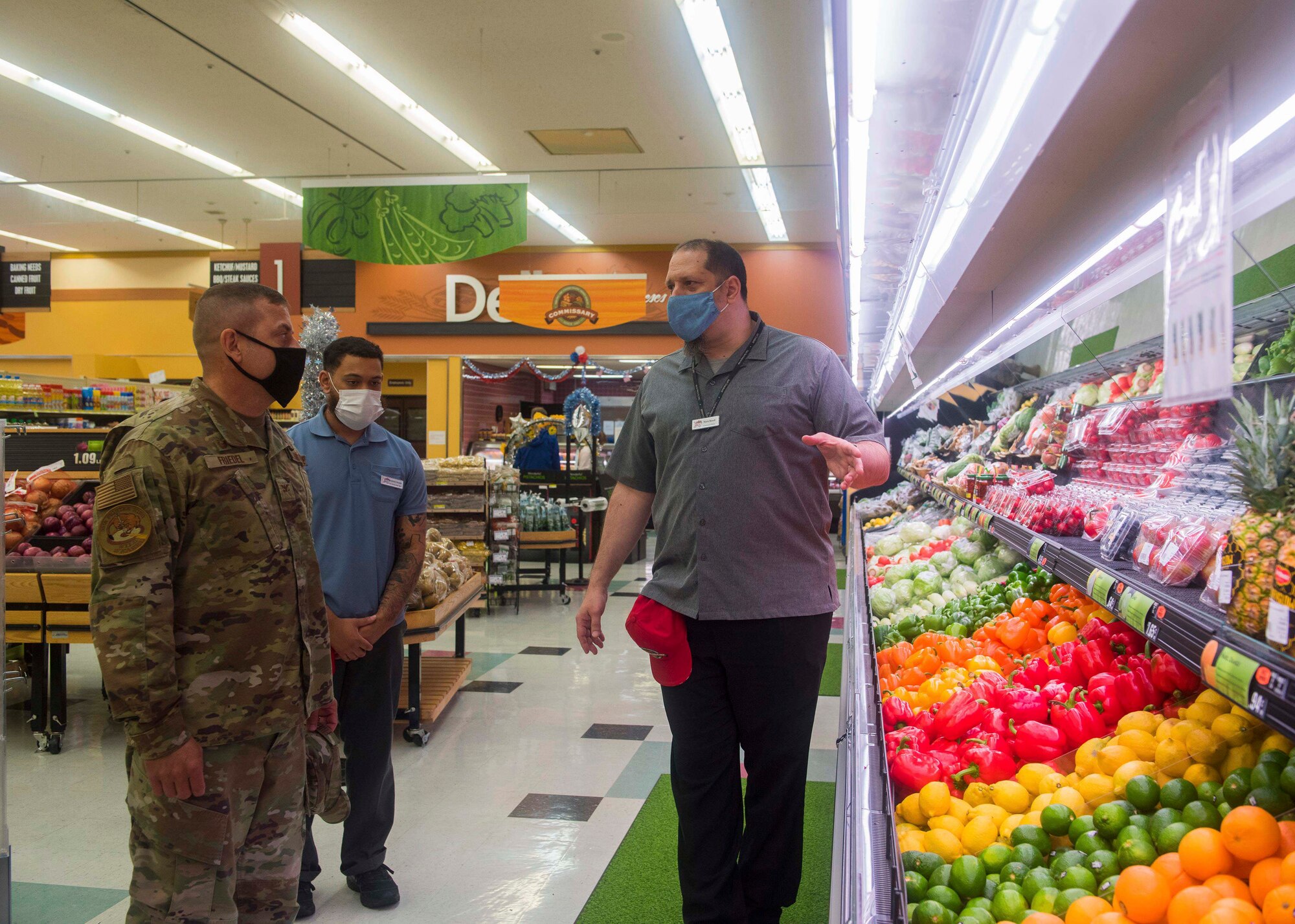 A commissary worker points out the produce to a military member.